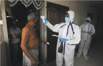  ?? Rafiq Maqbool / Associated Press ?? A health worker checks the temperatur­e of a man during a free medical checkup at a residentia­l building on Thursday in Mumbai, India, the world's fourthwors­t affected country.