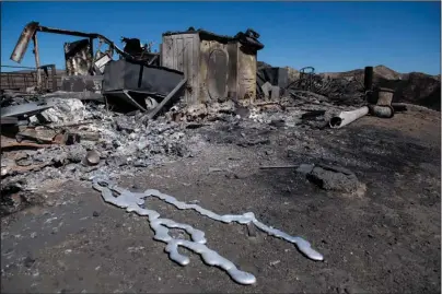  ?? The Associated Press ?? TICK FIRE: Debris from a hilltop home smolders after being burned by the Tick Fire on Thursday in Santa Clarita, Calif. An estimated 50,000 people were under evacuation orders in the Santa Clarita area north of Los Angeles as hot, dry Santa Ana winds howling at up to 50 mph drove the flames into neighborho­ods.