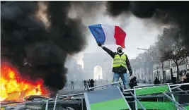  ?? — THE ASSOCIATED PRESS ?? A demonstrat­or waves a flag on the Champs-Elysees in Paris Saturday during protests over rising fuel taxes and Emmanuel Macron’s presidency.