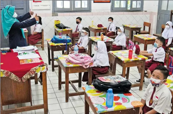  ?? (AP/Dita Alangkara) ?? Students wearing face masks to help prevent the spread of covid-19 attend a class Monday at an elementary school in Jakarta, Indonesia.