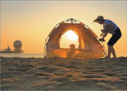  ?? TANG KE / FOR CHINA DAILY ?? A camper plays with her dog in Yantai, Shandong province, on July 25.