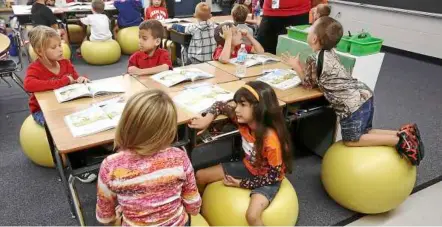  ??  ?? Better than chairs: Sitting on exercise balls help the children focus better. — mcT