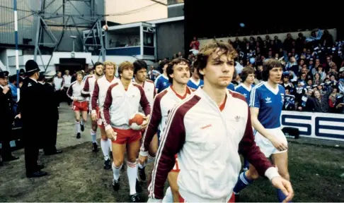  ??  ?? AZ ‘67, met Richard van der Meer voorop, betreedt Portman Road Stadium voor de heenwedstr­ijd van de UEFA Cup-finale van 1981. Rechts Arnold Mühren van Ipswich Town.