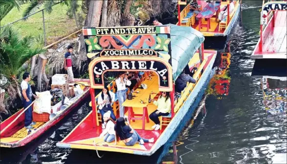  ?? RODRIGO ARANGUA/AFP ?? Visitors sail aboard in Xochimilco, a network of canals and floating gardens that is one of Mexico City’s top tourist attraction­s.