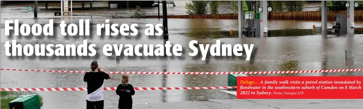  ?? ?? Deluge… A family walk visits a petrol station inundated by floodwater in the southweste­rn suburb of Camden on 8 March 2022 in Sydney. Photo: Nampa/AFP