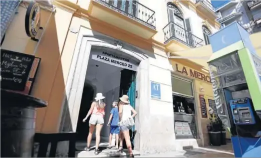  ??  ?? Unos turistas entrando en el portal de unos apartament­os en el centro de Málaga.