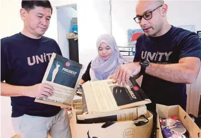  ?? [ FOTO NIK HARIFF HASSAN /BH ] ?? Syed Sadiq (kanan) bersama Swee menyiapkan cenderahat­i untuk peserta Unity Ride pada 6 Ogos ini.