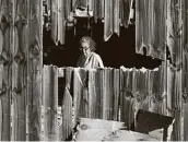  ??  ?? A woman looks through the hole in her fence as she inspects the damage in her yard following the storm.