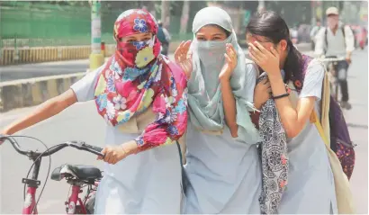  ?? PTI ?? Girls cover their faces with scarves to protect themselves from the scorching heat in Allahabad on Monday. —