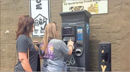  ?? Doug Walker ?? Anna Zebeau (left) watches as Dancie Pruitt makes a parking payment at the kiosk behind Harvest Moon.