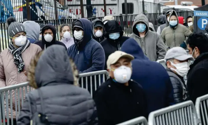  ?? Photograph: John Minchillo/AP ?? Patients wear personal protective equipment while maintainin­g physical distancing as they wait in line coronaviru­s tests at Elmhurst hospital center on Wednesday.