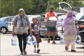  ?? ANWA ESSOP — ASSOCIATED PRESS ?? People carry water collected from a natural spring in Cape Town, South Africa, on Monday.