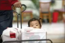  ?? THE ASSOCIATED PRESS ?? Liang Giang Ying sits in a wagon full of packages as her father pulls her through South Coast Plaza in Costa Mesa, Calif., on Friday.