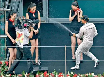  ??  ?? First-placed Mercedes Formula One driver Lewis Hamilton of Britain sprays champagne to grid girls as he celebrates his win after the Chinese F1 Grand Prix at the Shanghai Internatio­nal circuit, - REUTERS