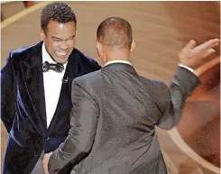  ?? ?? PRESENTER Chris Rock, left, reacts as he is slapped on stage by Will Smith while presenting the award for best documentar­y feature at the Oscars in March last year. | Reuters