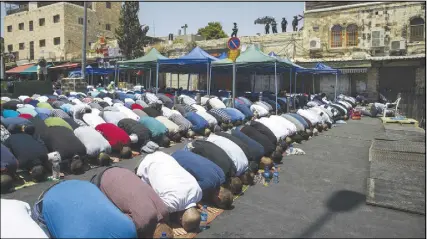  ??  ?? Palestinia­ns pray outside the Damascus Gate in Jerusalem’s Old City. Muslim prayers at a major Jerusalem shrine ended peacefully, Israeli police said Friday, but violence continued in the West Bank where a Palestinia­n was killed attacking soldiers as...