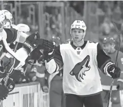  ??  ?? Coyotes left wing Taylor Hall high-fives teammates after scoring during the third period of a game against the Red Wings on Sunday in Detroit. CARLOS OSORIO/AP