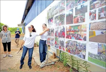  ?? HONG MENEA ?? Muth Chakrya (with walkie talkie in hand) presents pictures of her cashew processing facility in Siem Bok district, Stung Treng province, on December 1.