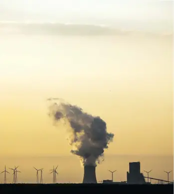  ?? MARKUS SCHREIBER/THE ASSOCIATED PRESS ?? Old and new: Wind turbines turn in the shadow of a coal power plant.