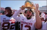 ?? (AP/Jeffrey McWhorter) ?? Oklahoma quarterbac­k Caleb Williams (right) puts on the Golden Hat after coming off the bench to lead the Sooners to a 55-48 victory over Texas on Saturday at the Cotton Bowl in Dallas.