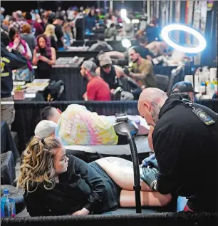  ?? SEAN D. ELLIOT THE DAY ?? Brian Hubis of Boston inks a tattoo on the thigh of his girlfriend Samantha Carson during the inaugural New England Tattoo Expo on Saturday at the Mohegan Exposition and Convention Center. Hubis hoped to complete the tattoo in time to enter it into one of the contests as part of the expo.