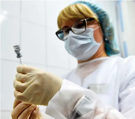  ?? AFP ?? Above, a nurse prepares a dose of Russia’s new coronaviru­s disease vaccine, named Sputnik V, (below left) developed by the Gamaleya Institute in Moscow.