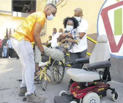  ?? (Photos: Garfield Robinson) ?? Garfield Virgin (right) and his son Brandon place quadripleg­ic Shushanna Thomas in her new motorised wheelchair on Thursday at Virgin Internatio­nal Trading on Chisholm Avenue, St Andrew. Virgin, who bought the wheelchair for Thomas after seeing her Christmas wish on TVJ, is driven to help disabled people because he almost lost his son at birth.