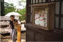  ??  ?? A woman looking at cat figurines called “maneki-neko” .