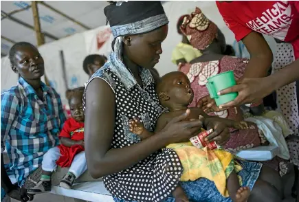  ?? GETTY IMAGES ?? A South Sudanese refugee’s malnourish­ed baby is given nutritiona­l supplement­s provided by the UN World Food Programme at a camp in Uganda. Food supplies in South Sudan have been badly disrupted by an ongoing civil war, and famine was declared there in...