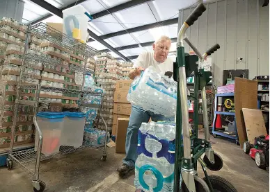  ?? Staff photo by Evan Lewis ?? n Harlan Jones, an emergency disaster volunteer with The Salvation Army, loads water that will be put on the corps’ response vehicle Friday in Texarkana. Local volunteers have been put on standby in case they have to be deployed to South Texas after...