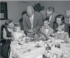  ??  ?? En la foto, Eisenhower y su familia disfrutan de la cena de Acción de Gracias en Augusta, Georgia. De izda. a dcha.: Mamie Eisenhower sosteniend­o a su nieta Susan; el presidente; su hijo John David Eisenhower y su mujer, Barbara, y delante de estos sus hijos David y Barbara, los otros nietos de Dwight.