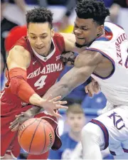  ?? [AP PHOTO] ?? AT LEFT: Kansas center Udoka Azubuike and Oklahoma center Jamuni McNeace reach for a loose ball during Monday’s game in Lawrence, Kan.