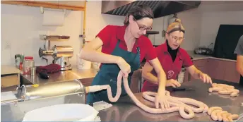  ??  ?? Avec l’aide d’une de ses employées, Geneviève prépare des saucisses au poulet, un des produits vedettes de la Ferme Johel.