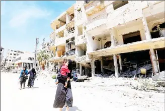  ?? (AFP) ?? Syrians walk down the street past destroyed buildings in Douma on the outskirts of Damascus on April 16, 2018 during an organised media tour after the Syrian army declared that all anti-regime forces have left Eastern Ghouta, following a blistering two...