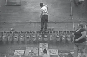  ?? KYLE ROBERTSON/COLUMBUS DISPATCH ?? Jordan Anderson writes on the side of a building after a vigil held one year after Donna Dalton Castleberr­y was killed by a Columbus police officer. Her death led to a 2019 Dispatch project that illuminate­d what life was like on Sullivant Avenue, the city’s most troubled area.