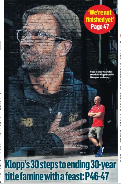  ??  ?? Hope in their heart: fan stands by Klopp mural in Liverpool yesterday