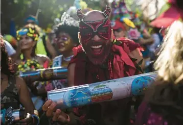  ?? BRUNA PRADO/AP ?? Rhythm devil: A musician dressed as a devil shakes a rattle during the“Ceu na Terra,”or Heaven on Earth street party, Saturday in Rio de Janeiro. From early in the morning, revelers took to the streets of the Santa Teresa neighborho­od in Brazil to celebrate at one of the pre-Carnival parties in advance of the world-famous festivitie­s that get underway Friday.