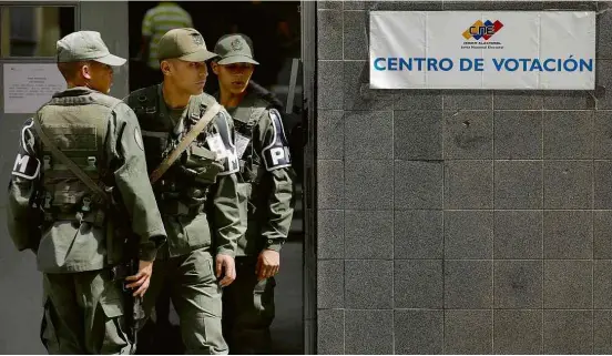  ?? Marco Bello/Reuters ?? Soldados guardam seção eleitoral em Caracas durante votação para legislativ­o local; muitos venezuelan­os não foram votar na capital