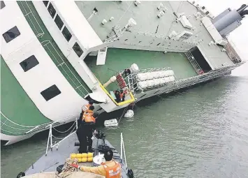  ??  ?? A file South Korea Coast Guard handout photo taken on April 16 some 20 kilometres off the island of Byungpoong in Jindo shows South Korea Coast Guard members rescuing some of the passengers and crew aboard a South Korean ferry sinking on its way to...