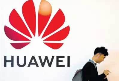  ?? AP ?? In this October 31, 2019 file photo, a man uses his smartphone as he stands near a billboard for Chinese technology firm Huawei at the PT Expo in Beijing.