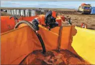  ?? IRINA YARINSKAYA / AGENCE FRANCE-PRESSE ?? A worker from the Russian Emergency Ministry tries to drain oil from the scene of a diesel spill outside Norilsk on Saturday.