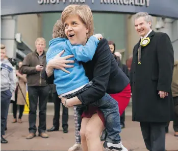  ?? CHIP SOMODEVILL­A/GETTY IMAGES ?? Scottish First Minister Nicola Sturgeon gets a hug from a boy on Monday while campaignin­g for SNP candidate Roger Mullin, right, in Kirkcaldy, Scotland. The United Kingdom general election is on Thursday, and some are speculatin­g Sturgeon’s Scottish...