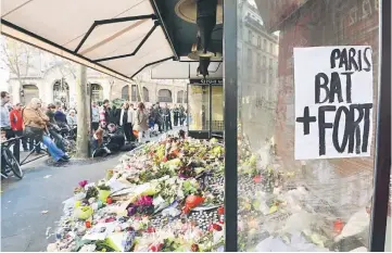  ??  ?? Mourners gather at a memorial site with flowers, candles and a sign reading ‘Paris beats stronger’, outside of the Le Belle Equipe, in the 11th district of Paris, for victims of the November 13 terrorist attacks in Paris. — AFP photo