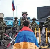  ?? Davit Ghahramany­an AFP/Getty Images ?? A PROTESTER holds the Armenian f lag near Russian troops in the Nagorno-Karabakh region Dec. 24.