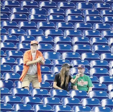  ?? LYNNE SLADKY/AP ?? Fans watch a game between the Marlins and Giants on May 30 in Miami. Major League Baseball’s average attendance of 26,854 is 1.4% below the 27,242 through the similar point last season, which wound up below 30,000 for the first time since 2003.