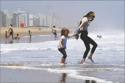  ?? ASSOCIATED PRESS ?? IN THIS MAY 22, 2020, FILE PHOTO, Victoria Faughnan (right) and Evelyn Faughnan play in the surf in Virginia Beach, Va., the day the state reopened the beachfront during the coronaviru­s pandemic.