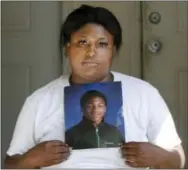  ?? THE ASSOCIATED PRESS ?? Monique Causey holds a portrait of her 14-year-old Malik, who was shot on Aug. 21, at her home in Chicago.