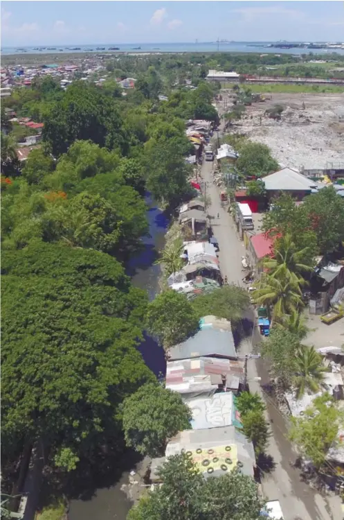  ??  ?? A row of shacks on the banks of the Butuanon river stretches along the road that leads to the landfill in Barangay Umapad, Mandaue City (in photo’s upper right corner). Some of the residents depend on the site’s trash to make a living.