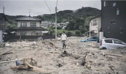  ?? Picture: AFP ?? CHAOS. A man walks down a devastated street after floods in Saka, Hiroshima prefecture yesterday. Japan’s Prime Minister Shinzo Abe warns of a race against time to save lives.