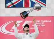  ?? /EFE ?? El piloto Lewis Hamilton lanza al aire el trofeo conquistad­o en el Gran Premio de Japón.